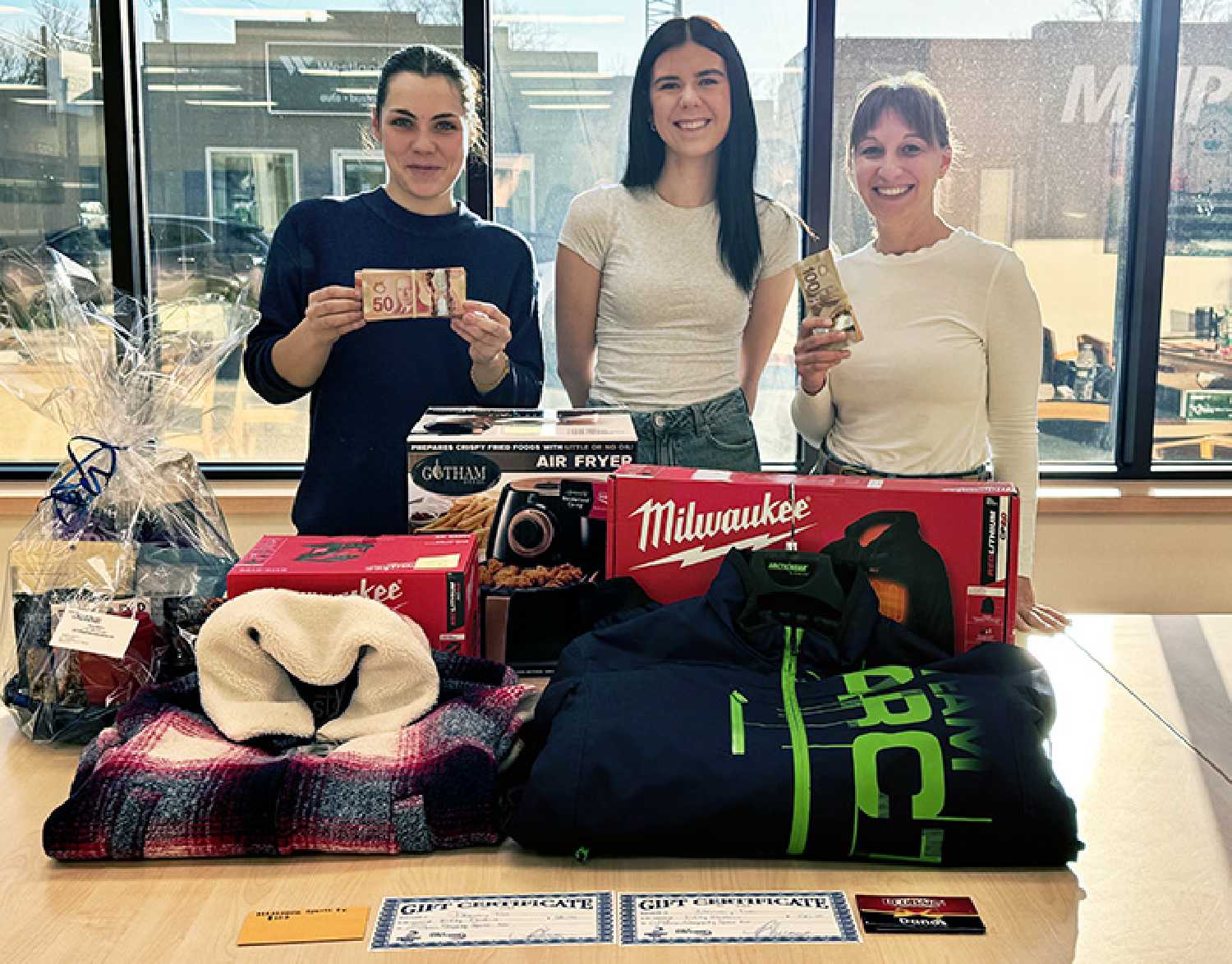The World-Spectator’s Nicole Taylor, Joey Light, and Kara Kinna with some of the prizes that will be given away in the World-Spectator Christmas Giveaway.